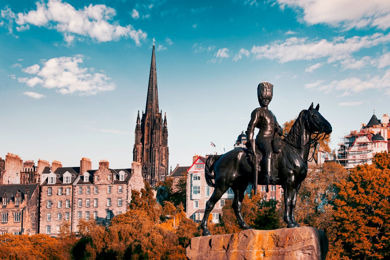 A stunning view of Edinburgh's gothic architecture and iconic statue under a vibrant sky.